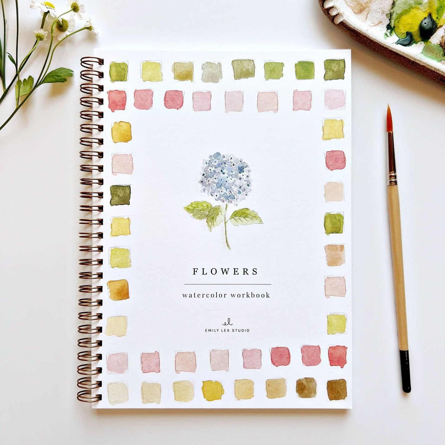 Watercolor workbook titled 'Watercolor Workbook Flowers' by Emily Lex Studio on a white surface with a brush and flowers.